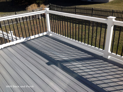 Deck with white vinyl railing, and black square aluminum balusters.