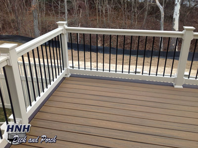Trex composite deck with almond vinyl railing and black round aluminum balusters.