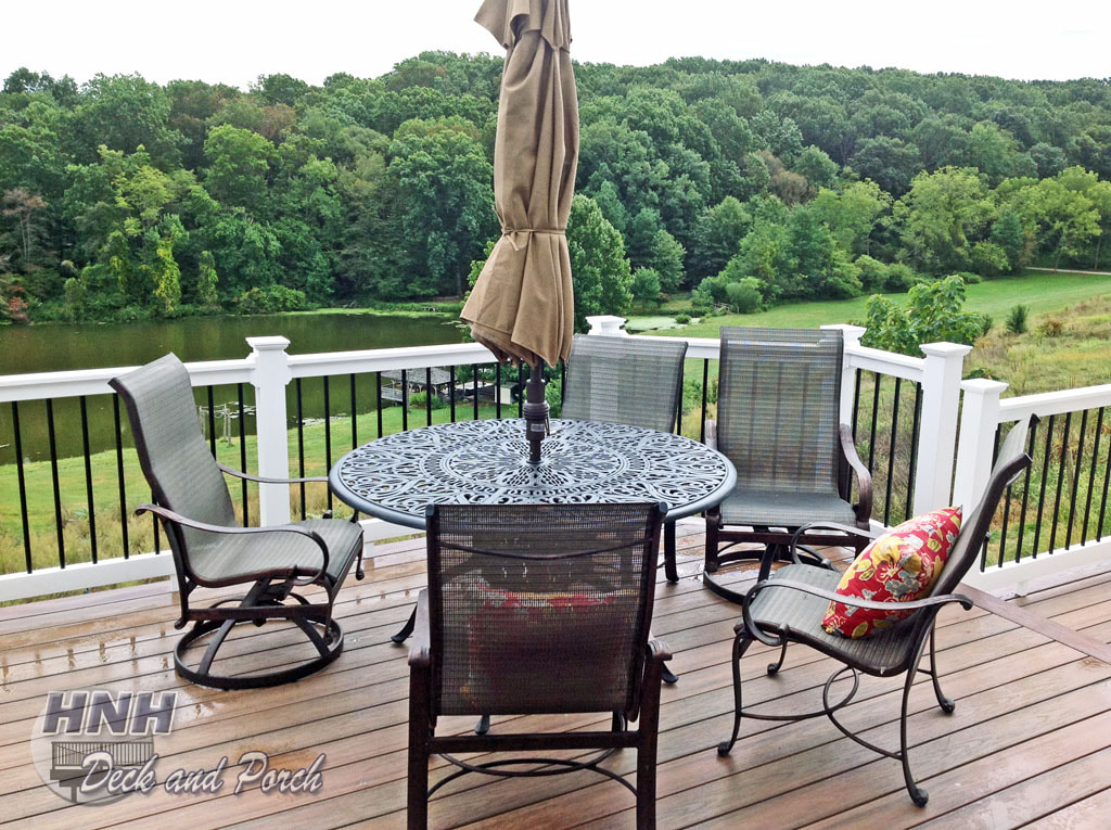 Wolf Tropical Hardwoods Collection PVC Decking with Amberwood flooring and Rosewood border with Deckorator's white vinyl railing and black round aluminum balusters.