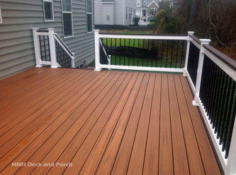 Composite deck using Trex Transcend Spiced Rum cap rail, white vinyl railing, and black square aluminum balusters.